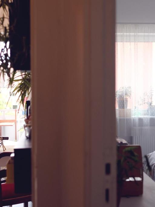 Ein Blick in zwei Räume. Links von der trennenden Wand ist die Küche mit angrenzendem Balkon zu sehen. Rechts das Schlafzimmer.
