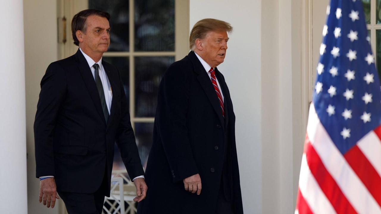 Der brasilianische Präsident Jair Bolsonaro und US-Präsident Donald Trump nebeneinander, rechts eine US-Flagge.