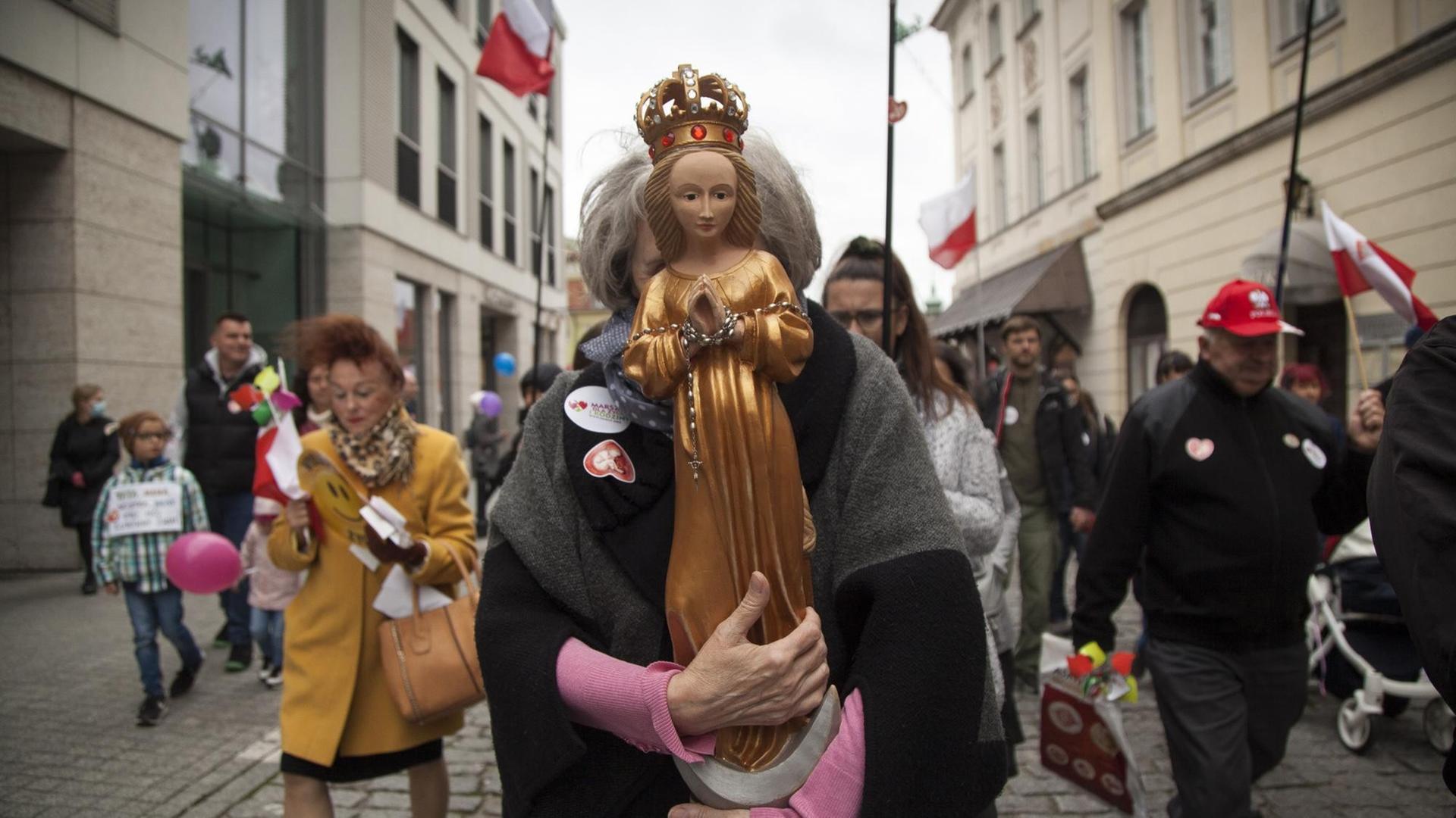 Eine Frau hält die Heilige Maria während des Nationalen Marsches für "Leben und Familie" vor ihr Gesicht, um für das traditionelle Verständnis der Ehe und des Lebens von der Empfängnis an zu demonstrieren. Eine Frau hält die Heilige Maria während des Nationalen Marsches für "Leben und Familie" vor ihr Gesicht, um für das traditionelle Verständnis der Ehe und des Lebens von der Empfängnis an zu demonstrieren.