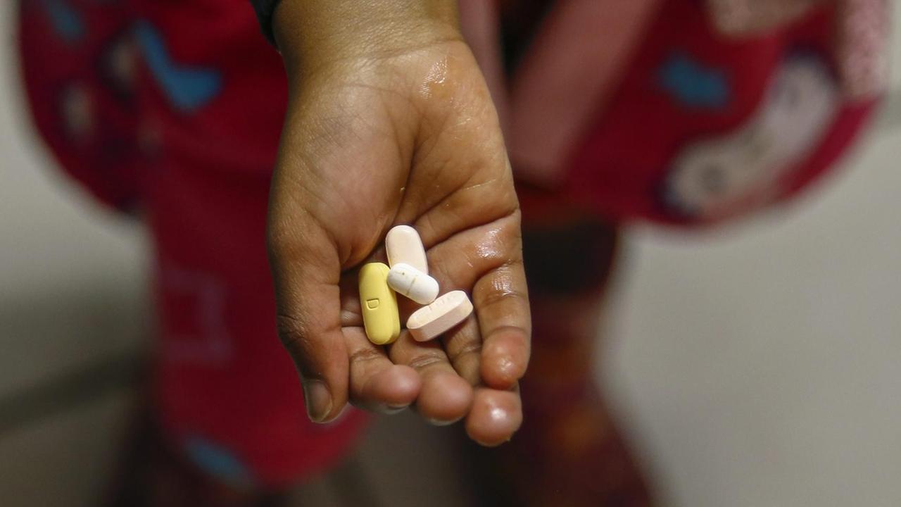 Ein südafrikanisches Kind hält antiretrovirale Medikamente in der Hand, mit der eine HIV-Infektion behandelt werden. Ein südafrikanisches Kind hält antiretrovirale Medikamente in der Hand, mit der eine HIV-Infektion behandelt werden.