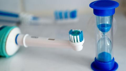 Eine Sanduhr und eine elektrische Zahnbürste symbolisieren den Aufruf der Zahnärzte, sich zum Zähneputzen ausreichend Zeit zu nehmen, um Zaherkrankungen wirksam vorzubeugen.