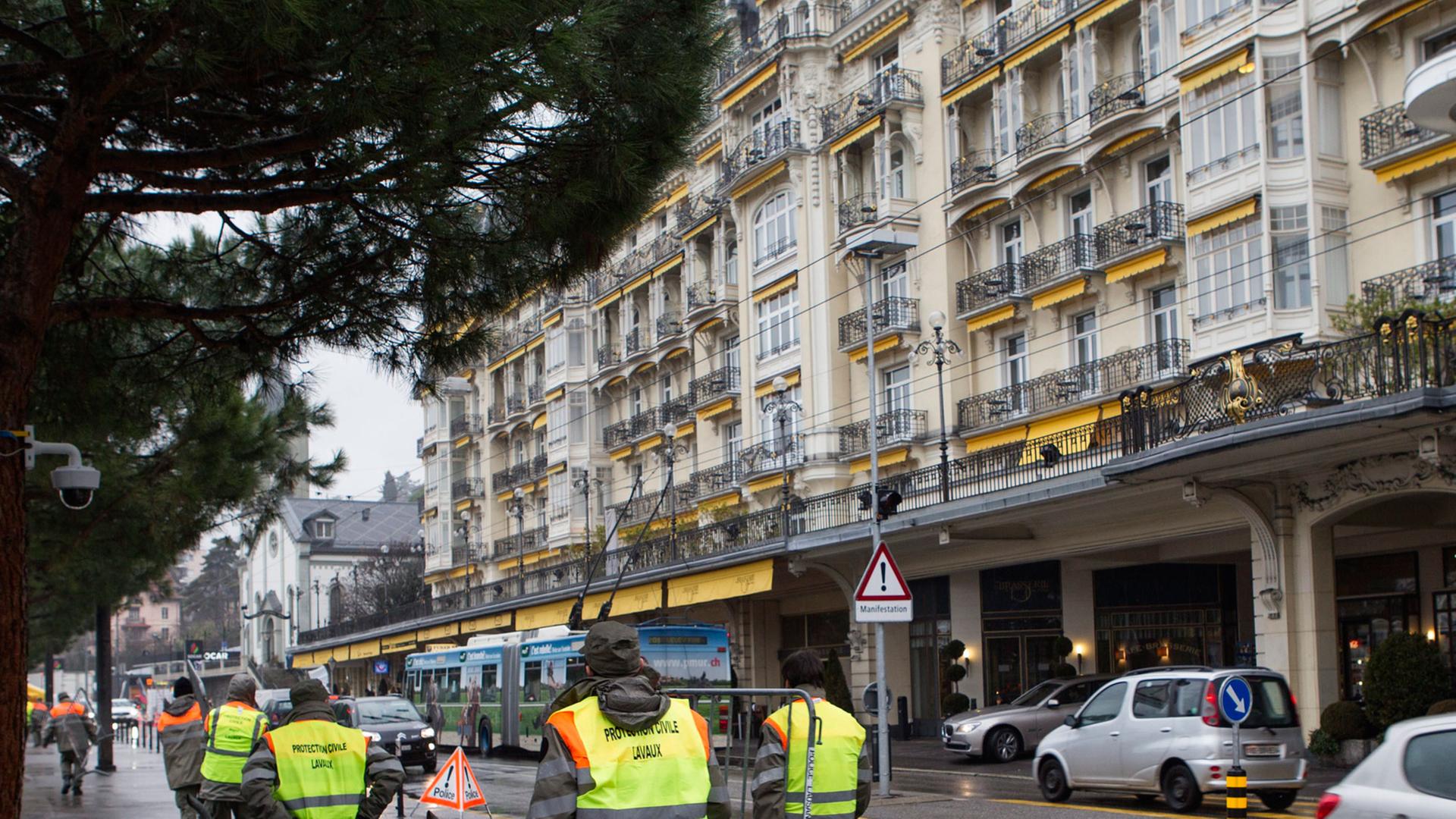 Sicherheitskräfte mit Warnwesten tragen eine Absperrung vor das 'Fairmont Le Montreux Palace' Hotel in Montreux in der Schweiz. Sicherheitskräfte mit Warnwesten tragen eine Absperrung vor das 'Fairmont Le Montreux Palace' Hotel in Montreux in der Schweiz.