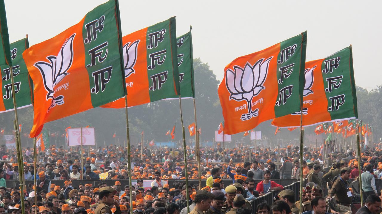 Anhänger des indischen Ministerpräsidenten Modi  halten Flaggen der rechtskonservativen hindunationalen Bharatiya Janata Partei in die Höhe.