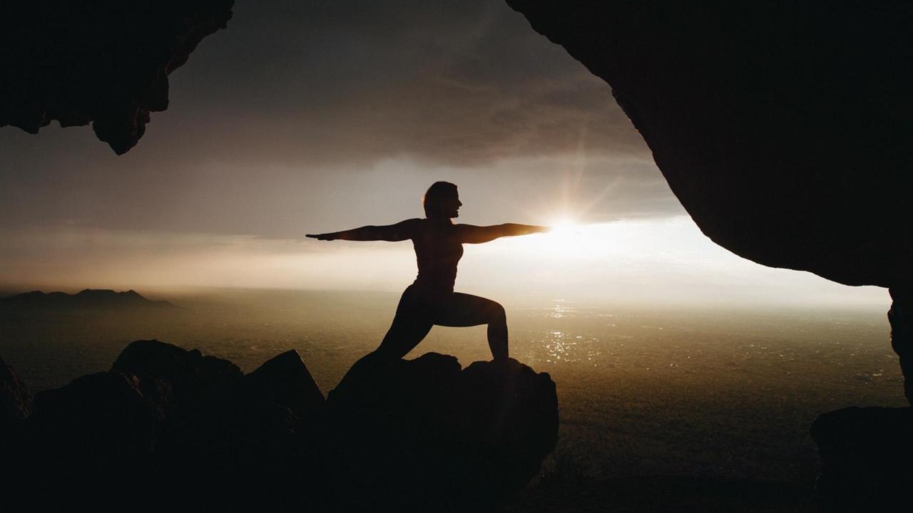 Eine Person macht an einem Felsen Yoga. Eine Person macht an einem Felsen Yoga.