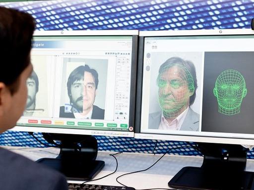 Ein Mann sitzt vor einem Computerbildschirm und arbeitet mit einem automatischen Gesichtserkennungssystem.