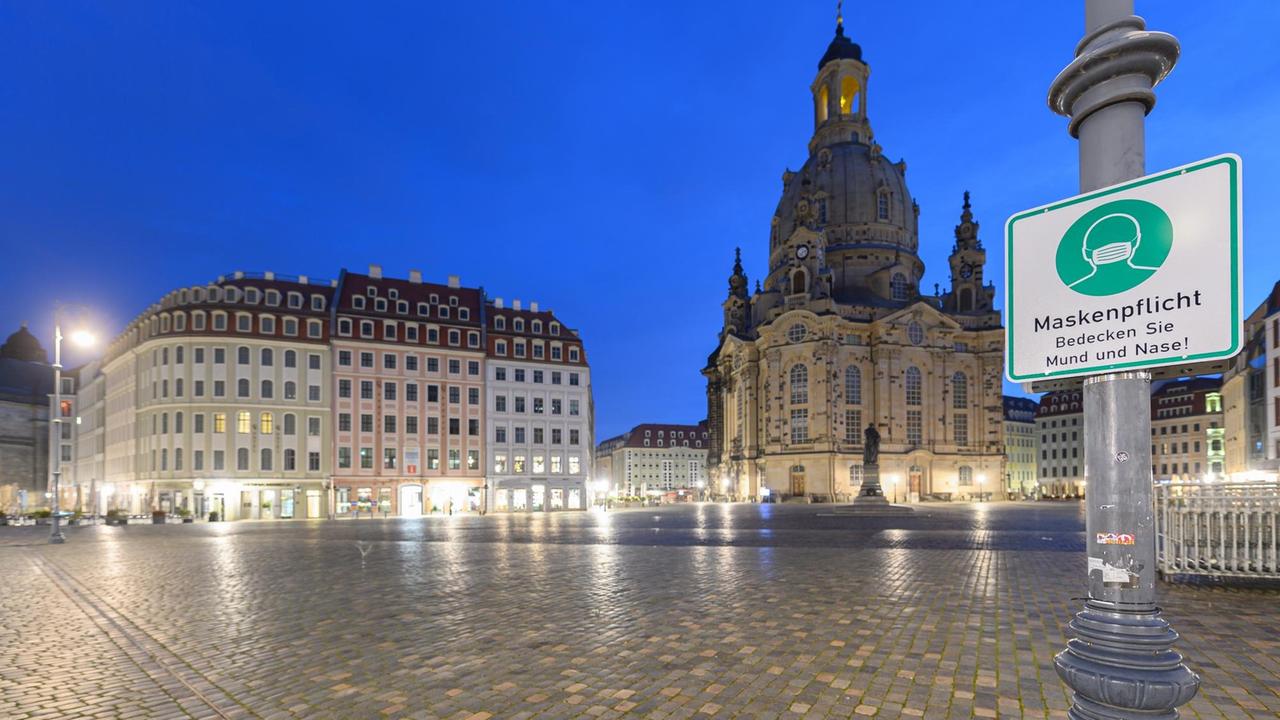 Ein Hinweisschild auf die Maskenpflicht hängt auf dem Neumarkt vor der Frauenkirche an einem Laternenmast. Ein Hinweisschild auf die Maskenpflicht hängt auf dem Neumarkt vor der Frauenkirche an einem Laternenmast.