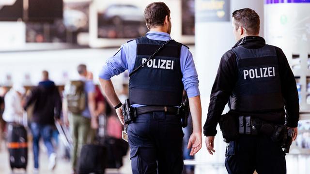 Zwei Polizisten mit Pistolen patrouillieren am Flughafen in Frankfurt am Main