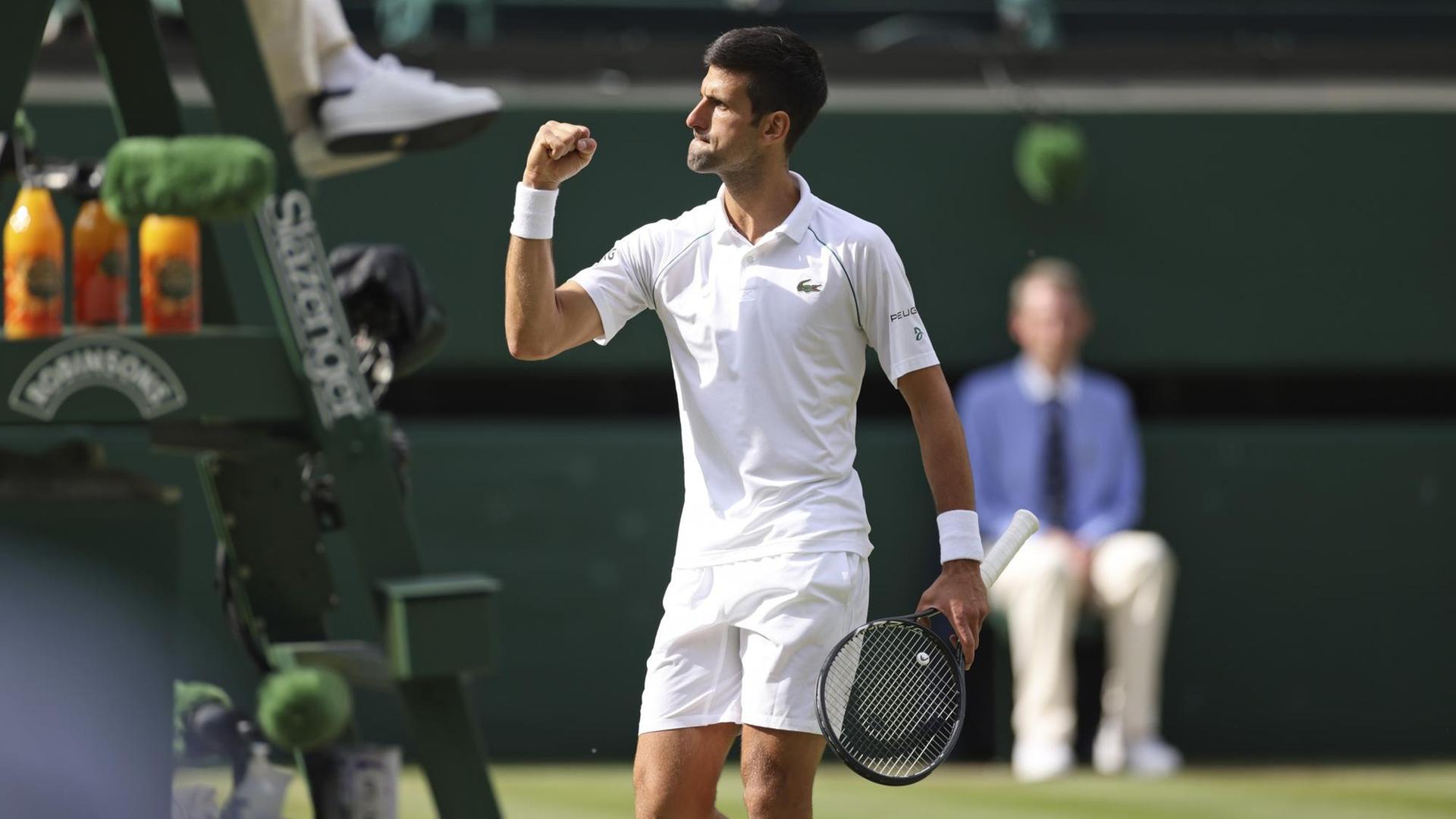 Novak Djokovic steht auf dem Tennis-Platz und hält eine Faust nach oben.