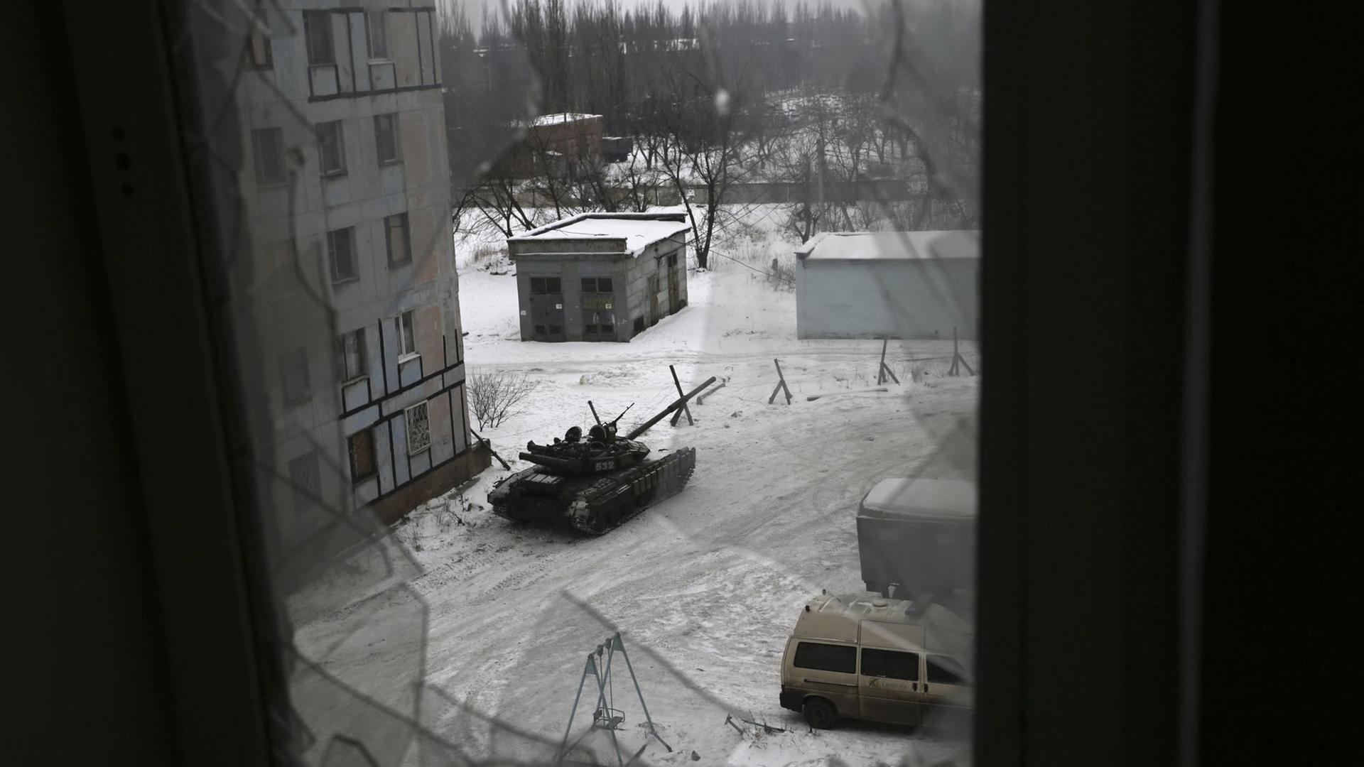 Blick durch ein zerstörtes Fenster auf einen Panzer der ukrainischen Armee in der Stadt Awdijiwka in der Ost-Ukraine. Blick durch ein zerstörtes Fenster auf einen Panzer der ukrainischen Armee in der Stadt Awdijiwka in der Ost-Ukraine.