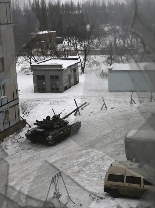 Blick durch ein zerstörtes Fenster auf einen Panzer der ukrainischen Armee in der Stadt Awdijiwka in der Ost-Ukraine.