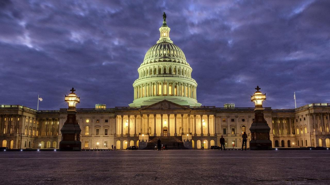 Das Bild zeigt das Kapitol in Washington, es dämmert gerade vor einem bewölkten Himmel. Im Gebäude sind viele Lichter eingeschaltet. Das Bild zeigt das Kapitol in Washington, es dämmert gerade vor einem bewölkten Himmel. Im Gebäude sind viele Lichter eingeschaltet.