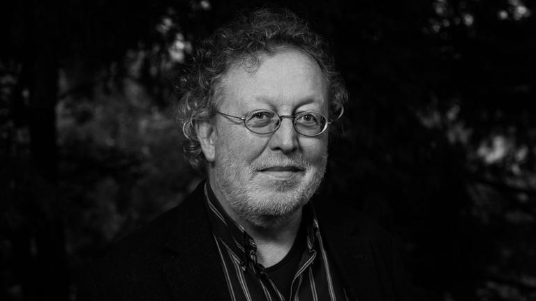 Wolfgang Hegewald hat lockige Haare, trägt eine Brille und einen Bart. Auf dem Schwarzweiß-Bild sind im Hintergrund dichte Baumkronen zu sehen. Wolfgang Hegewald hat lockige Haare, trägt eine Brille und einen Bart. Auf dem Schwarzweiß-Bild sind im Hintergrund dichte Baumkronen zu sehen.