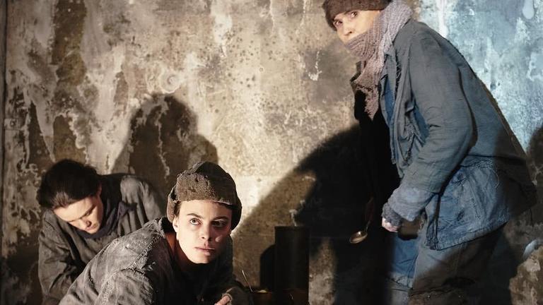 Szene aus dem Theaterstück "Am Kältepol": Frauen, die sich eingemummt kauern Szene aus dem Theaterstück "Am Kältepol": Frauen, die sich eingemummt kauern