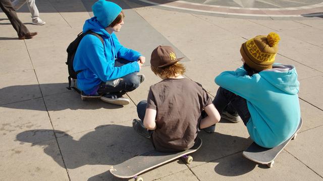 Junge Skateboardfahrer sitzen auf ihren Boards im Sommer 2011 am Alexanderplatz in Berlin.