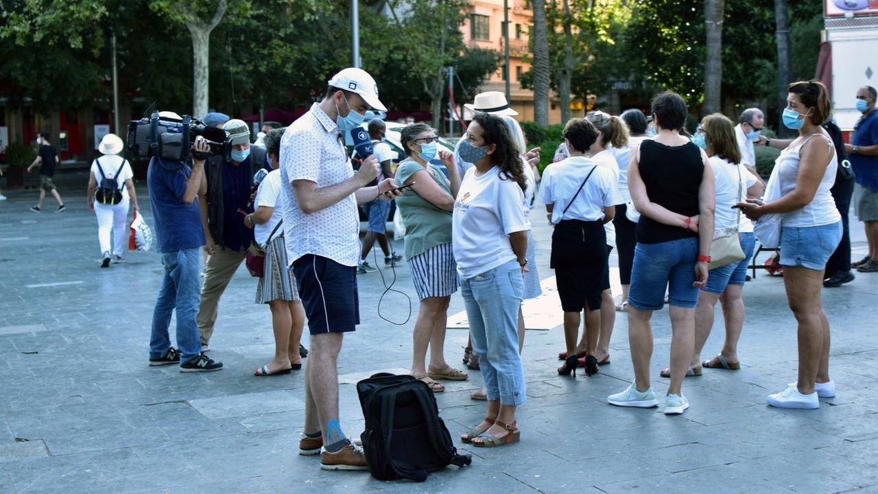 Reporter interviewt ein Zimmermädchen auf einer kleinen Demonstration Reporter interviewt ein Zimmermädchen auf einer kleinen Demonstration