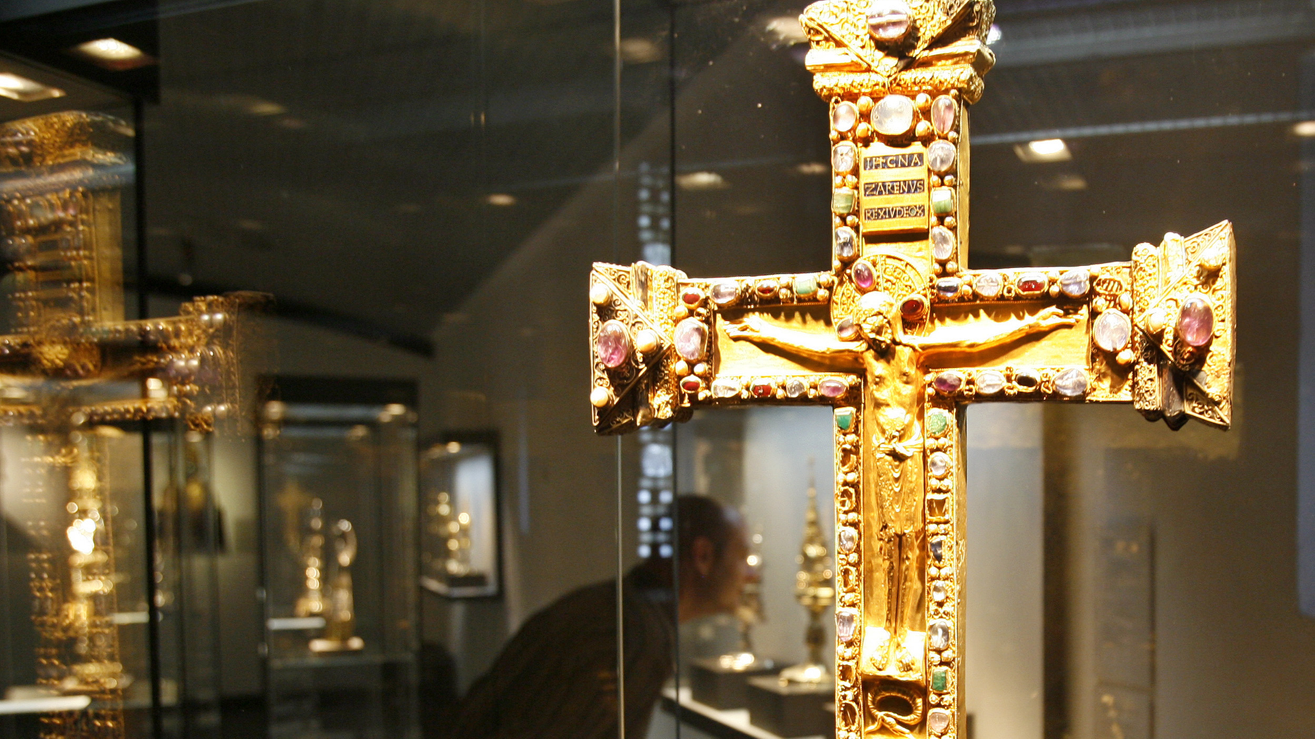 Hinter dem vergoldeten Otto-Mathildenkreuz aus der Zeit nach 982 betrachtet ein Mann am Freitag (22.08.2008) Exponate in der Domschatzkammer in Essen. Hinter dem vergoldeten Otto-Mathildenkreuz aus der Zeit nach 982 betrachtet ein Mann am Freitag (22.08.2008) Exponate in der Domschatzkammer in Essen.