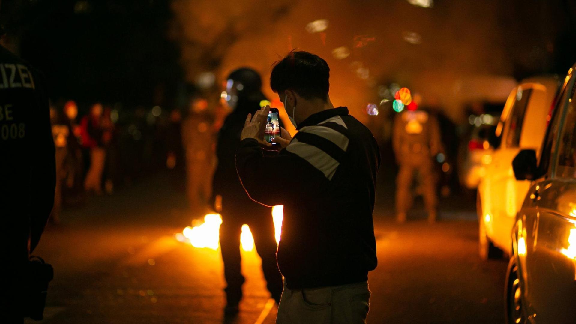 Ein Demonstrant steht am 1. Mai 2021 in Berlin Neukölln auf der Straße und hat sein Smartphone auf einen Polizisten gerichtet Ein Demonstrant steht am 1. Mai 2021 in Berlin Neukölln auf der Straße und hat sein Smartphone auf einen Polizisten gerichtet