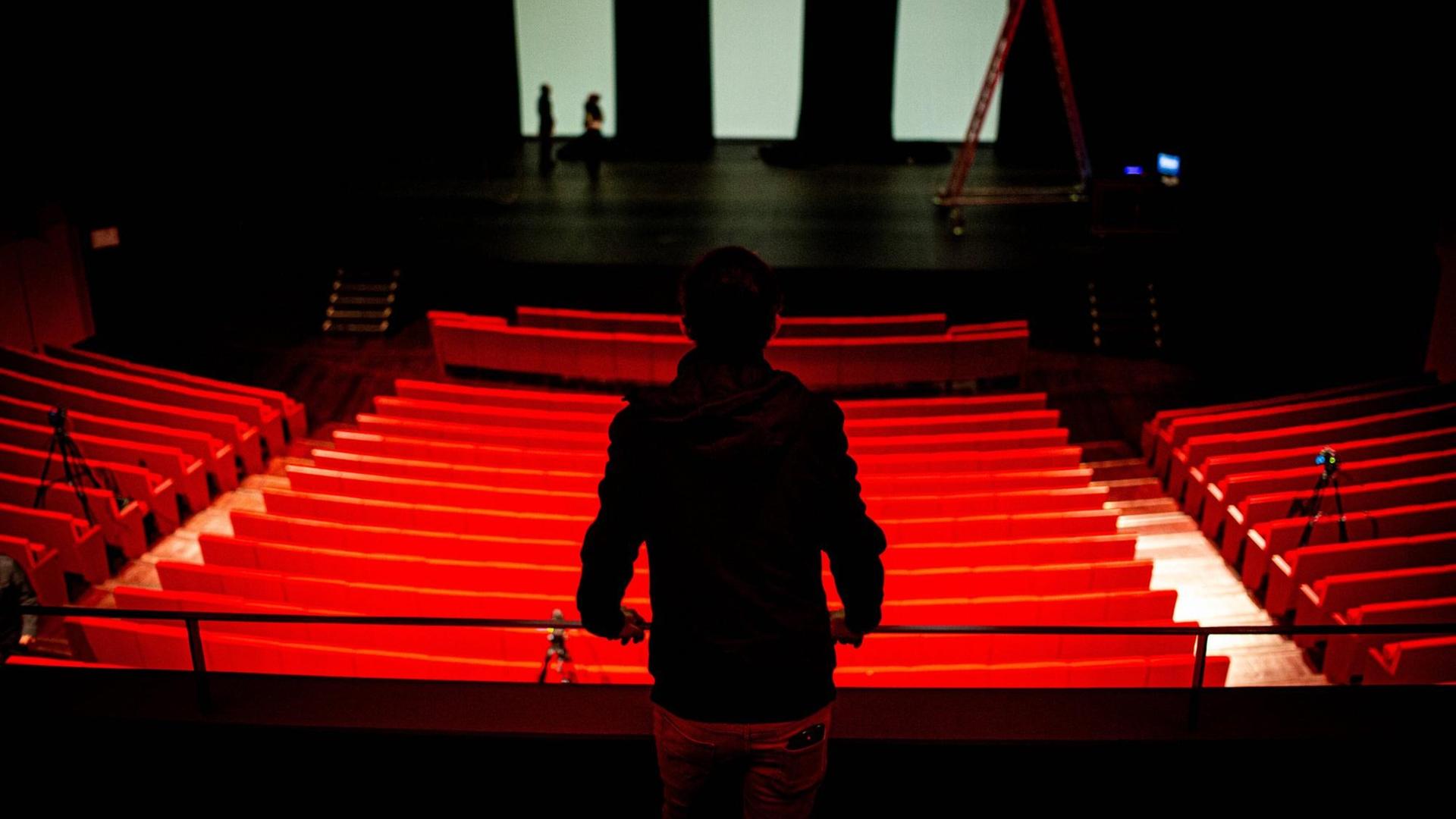 Ein Mensch blickt in ein leeres Theater.