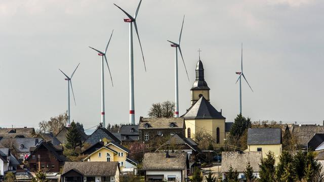 Der Ort Mörsdorf im Rhein-Hunsrück-Kreis mit der katholischen Kirche und hinter dem Ort fünf Windenergieanlagen.