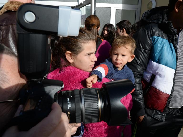 Mehrere Asylbewerber werden von Kamerateams und Fotografen umlagert.