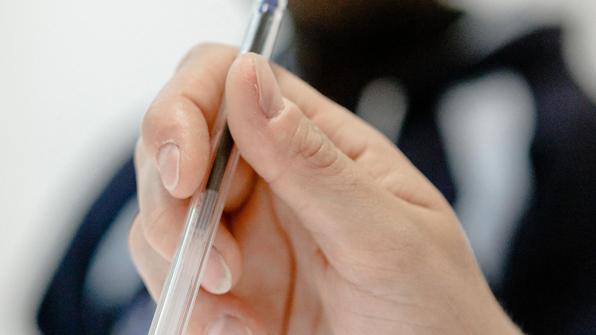Eine Frau hält einen Stift in der Hand. Eine Frau hält einen Stift in der Hand.