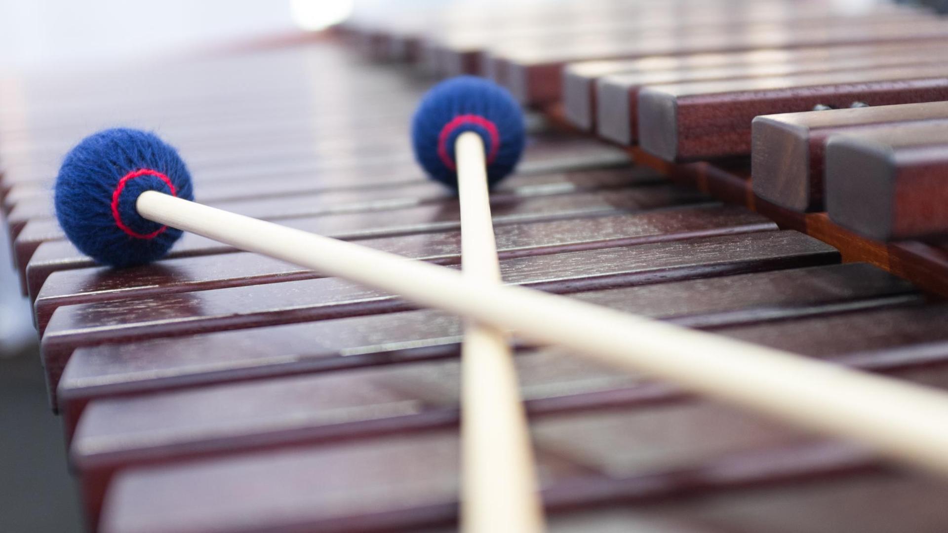 Zwei Schläger liegen auf den hölzernen Klangplatten eines Marimba. Zwei Schläger liegen auf den hölzernen Klangplatten eines Marimba.