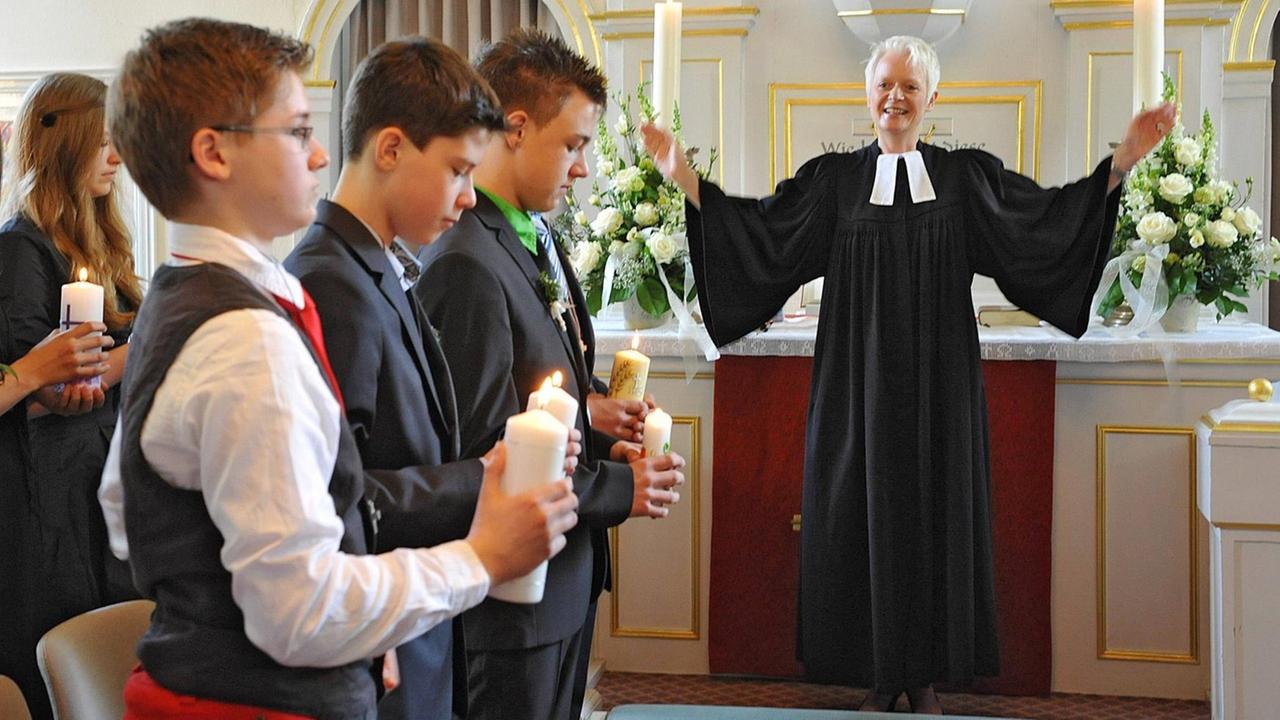 Eine Pfarrerin breitet bei einem Konfirmationsgottesdienst die Arme aus. Eine Pfarrerin breitet bei einem Konfirmationsgottesdienst die Arme aus.