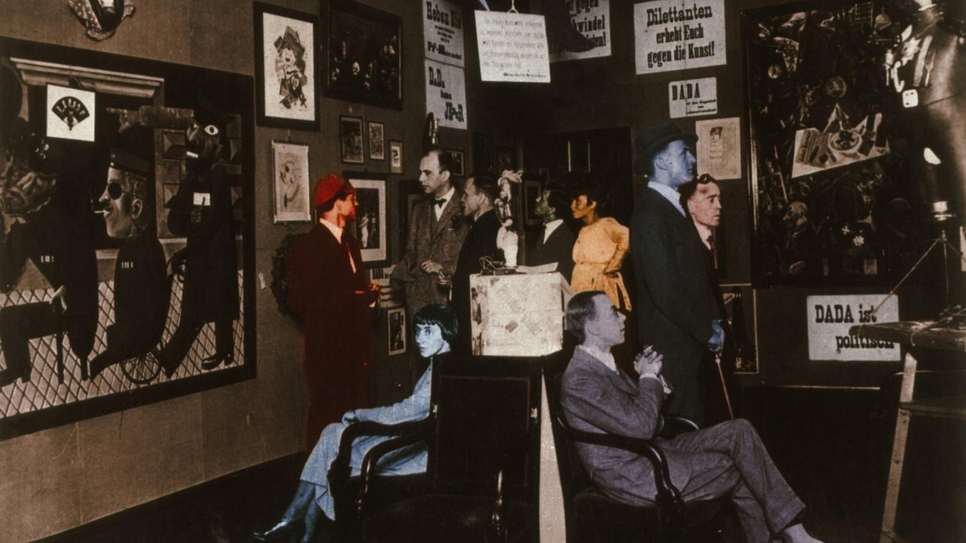 Eröffnung der 1. Internationalen Dada-Messe, Berlin, Buchhandlung Dr. Burchard, 5. Juli 1920 (v. li. stehend Raoul Hausmann, Otto Burchard, Baader, Wieland und Margarete Herzfelde, George Grosz, John Heartfield; sitzend Hannah Höch und Otto Schmalhausen. Foto, spätere Kolorierung. Eröffnung der 1. Internationalen Dada-Messe, Berlin, Buchhandlung Dr. Burchard, 5. Juli 1920 (v. li. stehend Raoul Hausmann, Otto Burchard, Baader, Wieland und Margarete Herzfelde, George Grosz, John Heartfield; sitzend Hannah Höch und Otto Schmalhausen. Foto, spätere Kolorierung.