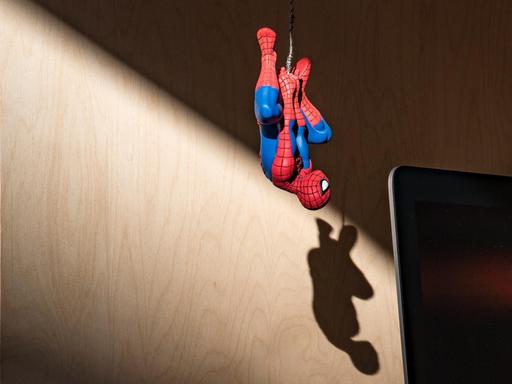 Eine Spiderman-Spielfigur hängt kopfüber vor einem Monitor.