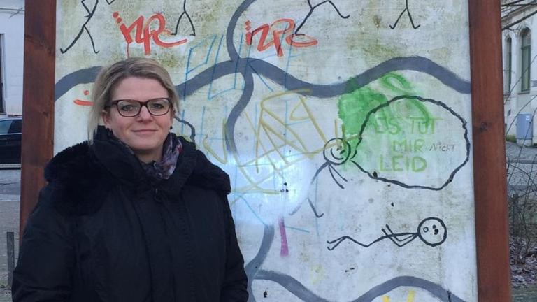 Die Linken-Politikerin Susanne Schaper steht vor einem Schild mit der gemalten Aufschrift "Gewaltfreier Lessingplatz".