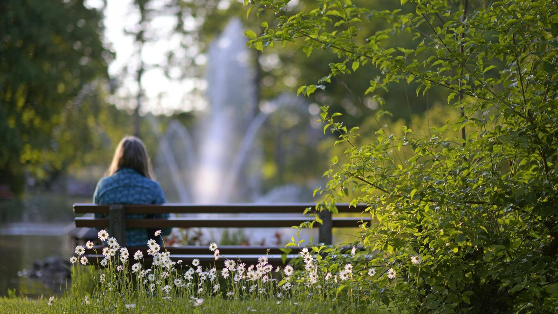 Eine Frau sitzt einsam auf einer Parkbank