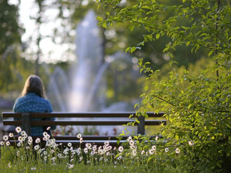 Eine Frau sitzt einsam auf einer Parkbank