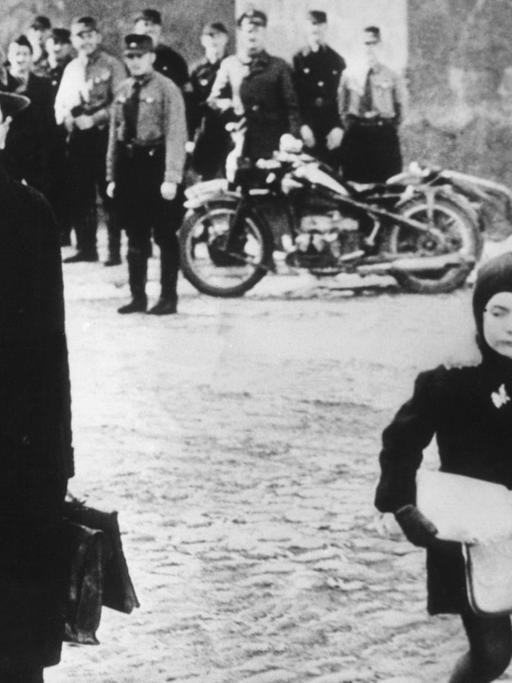 Eine jüdische Familie flüchtet unter dem Gelächter von Wehrmachtssoldaten