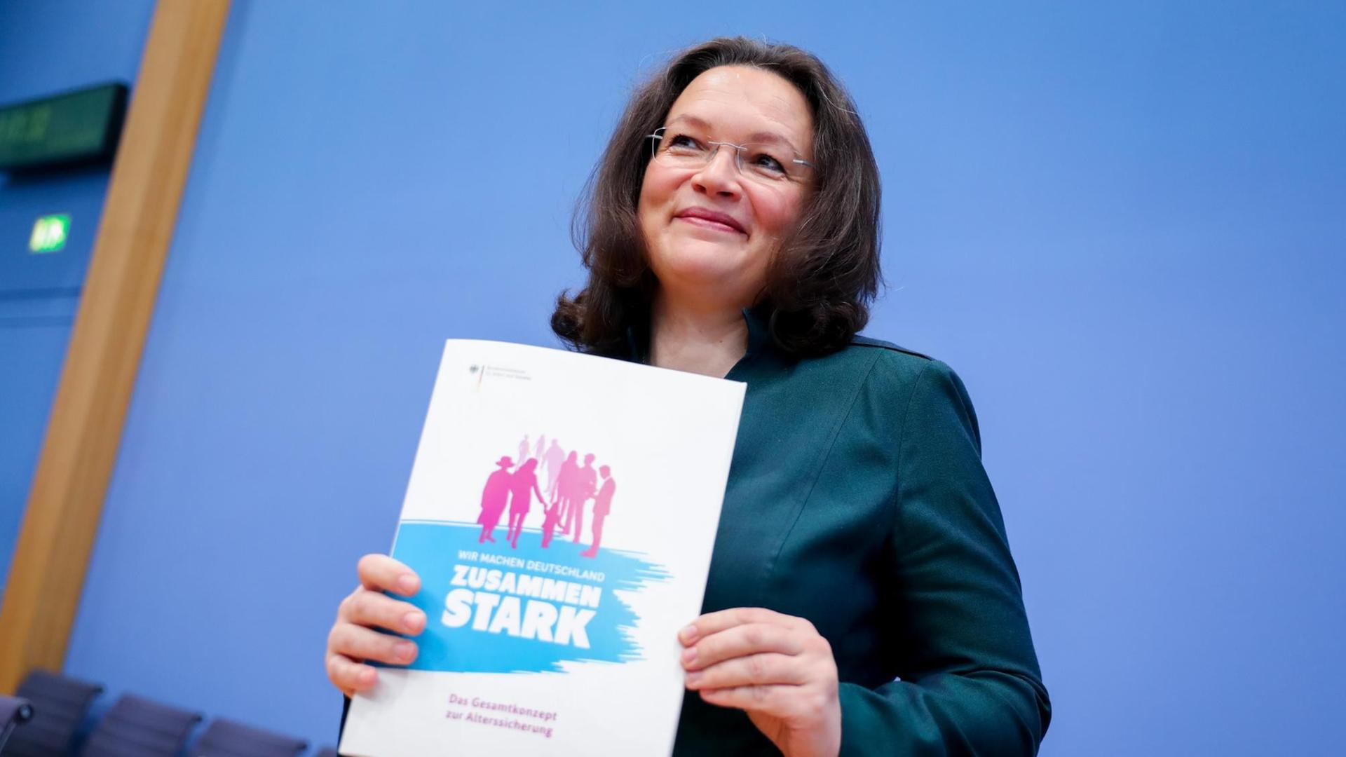 Bundesarbeits- und -sozialministerin Andrea Nahles (SPD) hält ein Din-A-4 großes Heft mit der Aufschrift "Zusammen stark" vor dem Oberkörper. Bundesarbeits- und -sozialministerin Andrea Nahles (SPD) hält ein Din-A-4 großes Heft mit der Aufschrift "Zusammen stark" vor dem Oberkörper.