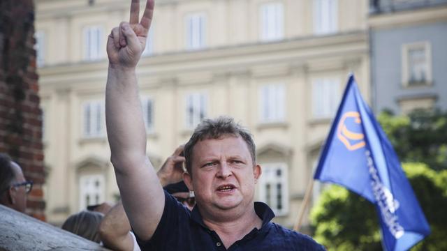 Tomasz Piatek steht am 12. Januar 2017 bei einem Protestmarsch gegen die Reform des Ponischen Justitzsystems in Krakau auf der Straße und streckt seine rechte Hand in die Luft, mit der er ein Peace-Zeichen macht.