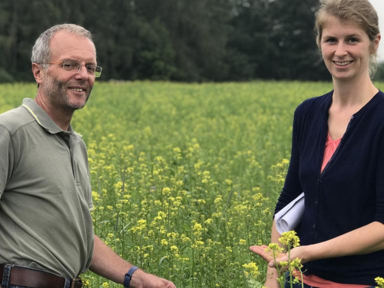 Die Landwirtin Cornelia Briem-Grooten steht zusammen mit dem Berater Georg Milz von der Landwirtschaftskammer NRW in einem blühenden Feld.