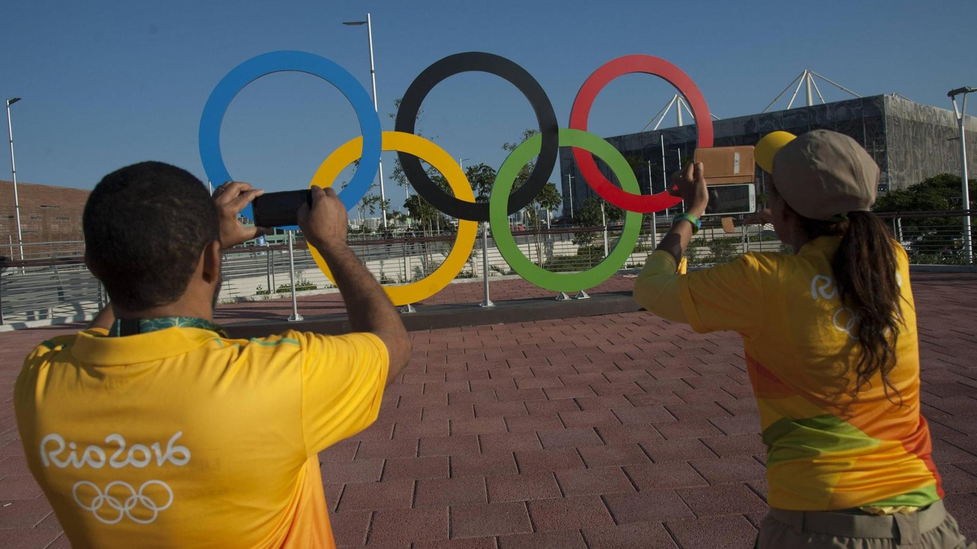 Olympia-Mitarbeiter machen ein Foto von den olympischen Ringen.