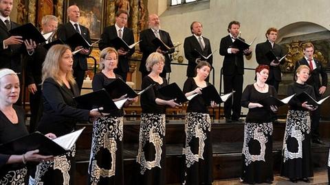 Frauen und Männer des Chores singen bei einem Konzert in einer Kirche.