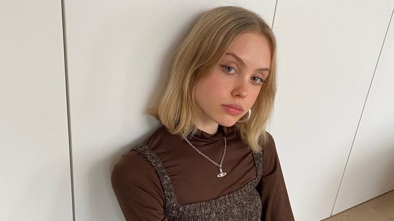 Porträt von Fanny Brauweiler, sie sitzt auf dem Boden und schaut von unten in die Kamera. Porträt von Fanny Brauweiler, sie sitzt auf dem Boden und schaut von unten in die Kamera.