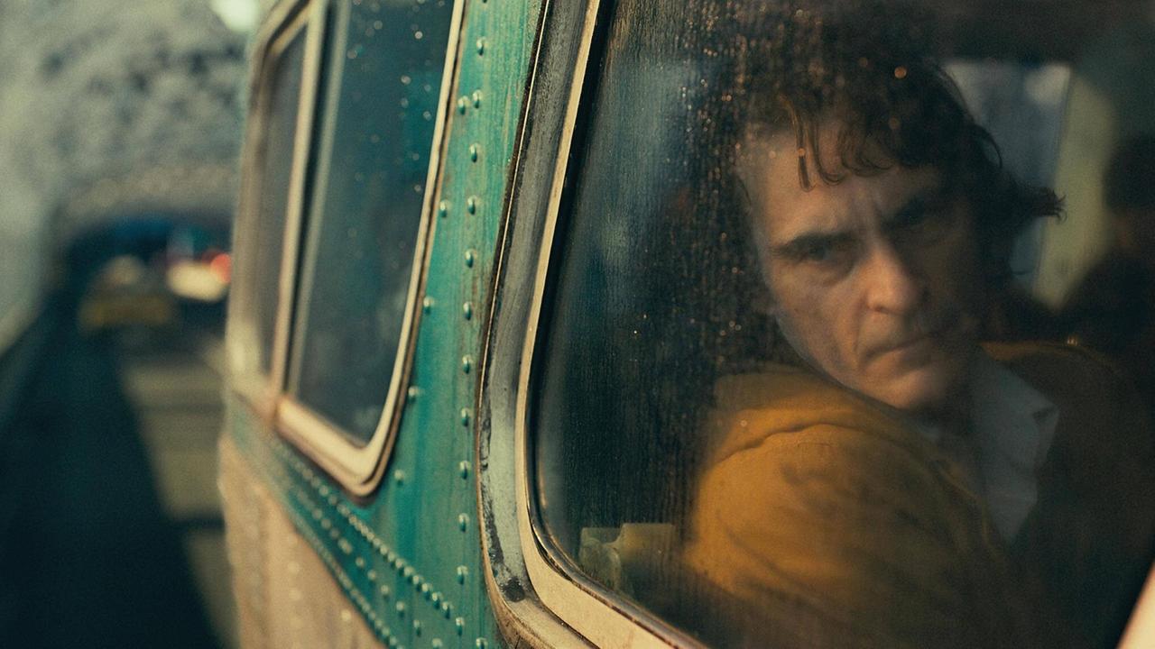 Der Schauspieler Joaquin Phoenix in einer Szene des Films "Joker". Er schaut melancholisch aus einem Autofenster auf eine verregnete, nächtliche Straße. Der Schauspieler Joaquin Phoenix in einer Szene des Films "Joker". Er schaut melancholisch aus einem Autofenster auf eine verregnete, nächtliche Straße.