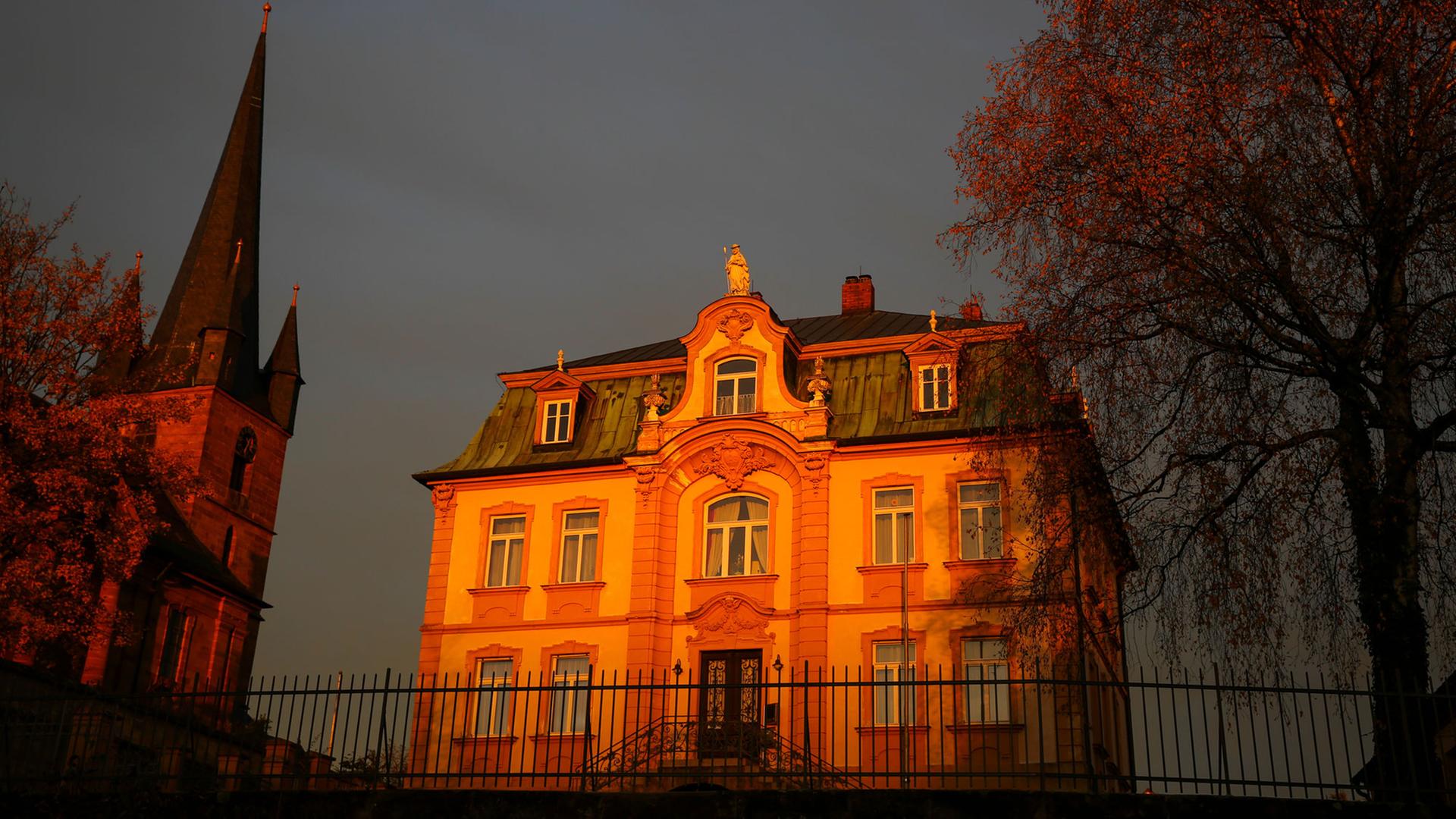 Die untergehende Sonne lässt die Kirche St. Wenzeslaus in Bayern und das zugehörige Pfarrhaus, einen neubarocken Bau im Villenstil orange aufleuchten. Die untergehende Sonne lässt die Kirche St. Wenzeslaus in Bayern und das zugehörige Pfarrhaus, einen neubarocken Bau im Villenstil orange aufleuchten.