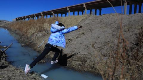 Eine Person springt über den fast ausgetrockneten Rio Grande an der Grenze zwischen den USA und Mexiko.