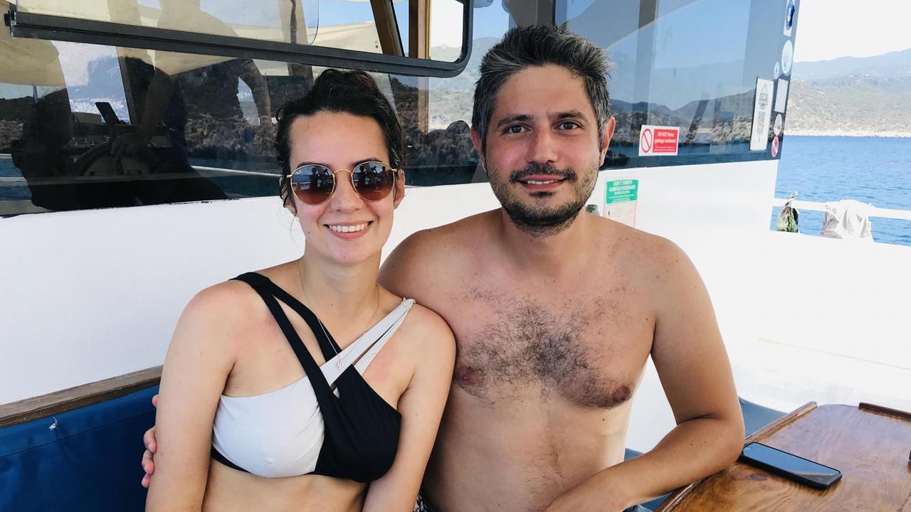 Ein junges Paar sitzt in Badekleidung an Bord eines Bootes.