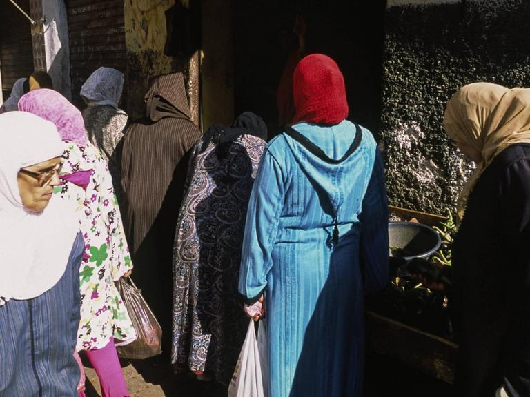 Frauen ziehen durch Altstadt von Casablanca und kaufen auf einem Strassenmarkt Lebensmittel ein.