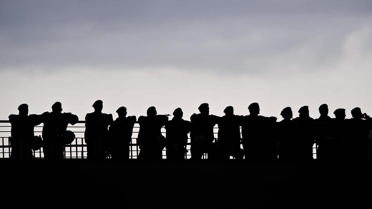 Silhouette einer Gruppe von Polizisten, die sich an ein Geländer lehnen. Silhouette einer Gruppe von Polizisten, die sich an ein Geländer lehnen.