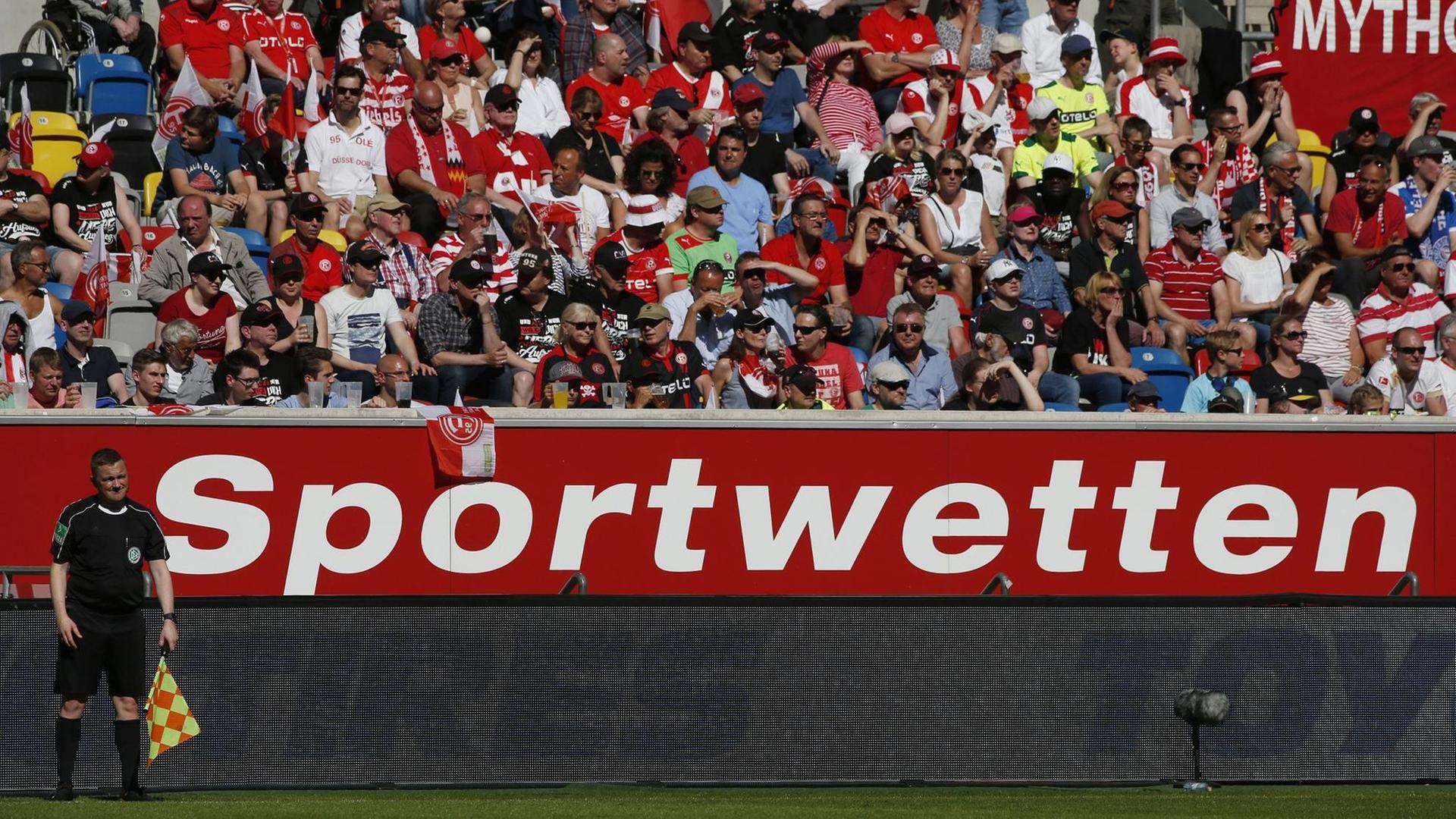 Arena in Düsseldorf bei einem Spiel am 06. 05. 2018: Der Schiedsrichter Assistent vor der Werbebande, die Werbung für Sportwetten zeigt. Arena in Düsseldorf bei einem Spiel am 06. 05. 2018: Der Schiedsrichter Assistent vor der Werbebande, die Werbung für Sportwetten zeigt.