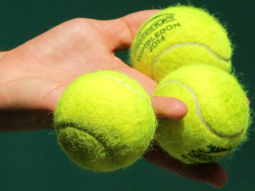 Drei Tennisbälle in der Hand eines Spielers
