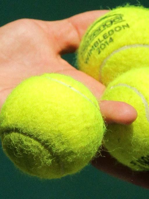 Drei Tennisbälle in der Hand eines Spielers