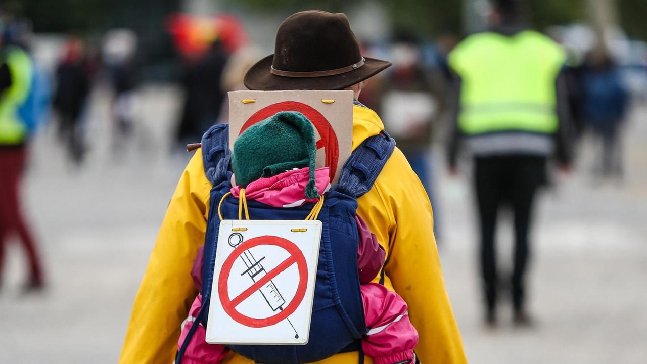 Eine Teilnehmerin einer Protestkundgebung der Initiative "Querdenken" trägt auf dem Cannstatter Wasen ein Schild gegen Impfungen auf ihrem Rücken Eine Teilnehmerin einer Protestkundgebung der Initiative "Querdenken" trägt auf dem Cannstatter Wasen ein Schild gegen Impfungen auf ihrem Rücken