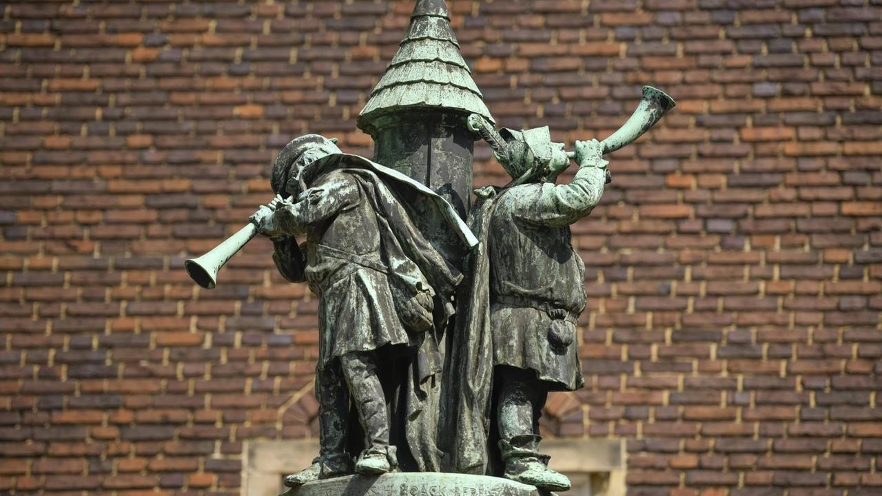 Bronzedenkmal mit Turm und darauf spielenden Musikern.
